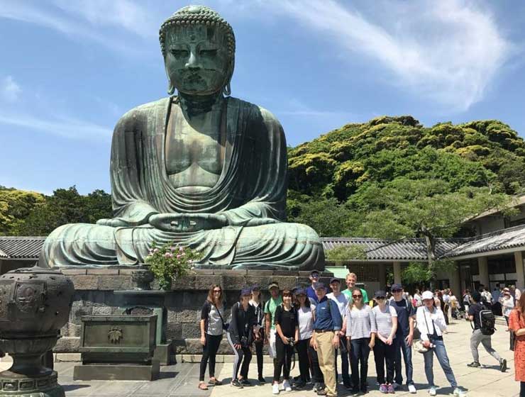 Photo of students by a Buddha statue